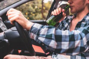 young crazy drunk man driving the car and drinking alcohol